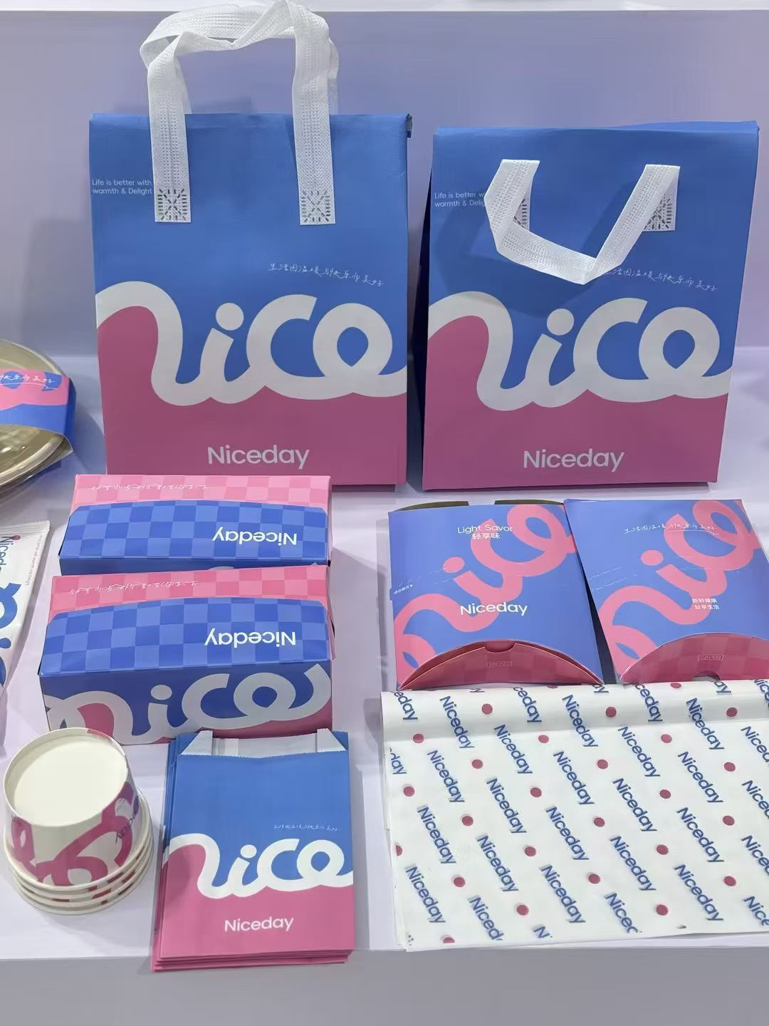 Reference photo showing a blue and pink branded cafe packaging range.